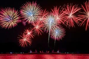 Amazing beautiful colorful fireworks display on celebration night, showing on the sea beach with multi color of reflection on water photo