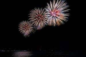 Amazing beautiful colorful fireworks display on celebration night, showing on the sea beach with multi color of reflection on water photo