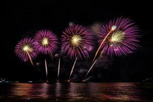 Amazing beautiful colorful fireworks display on celebration night, showing on the sea beach with multi color of reflection on water photo