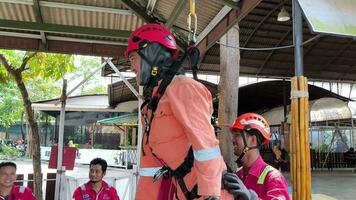 allí son personas en naranja trajes y cascos colgando en un cuerda video