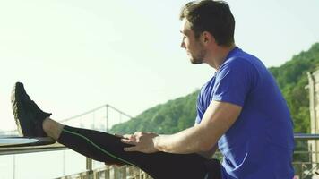 Handsome athletic man stretching his legs before morning outdoor workout video