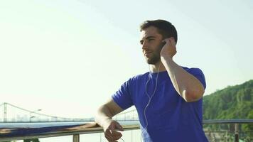 Happy handsome man enjoying listening to music outdoors after working out video