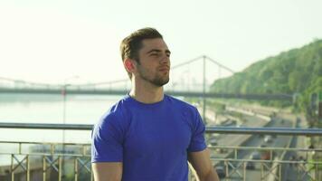 Handsome sportsman stretching his arms outdoors before working out video