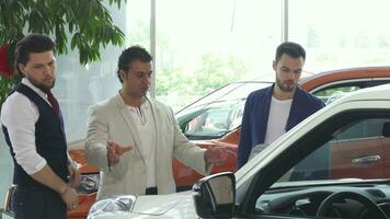 Three male friends examining car for sale at the dealership video