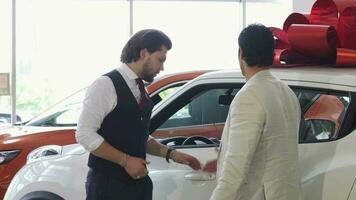 Professional car salesman opening door of a car for his male customer video