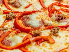 delicious pizza in the shape of pepperoni, salami, sausage, and pepper on a wooden table. top view photo