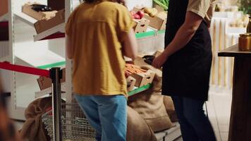 Vendor greeting first clients in newly opened zero waste supermarket, removing red ribbon. Storekeeper welcoming shoppers inside environmentally responsible local neighborhood store video