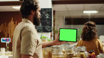 Customer using isolated screen tablet in zero waste supermarket to check ingredients for healthy recipe. Client in local grocery shop uses mockup device while shopping for pantry staples video