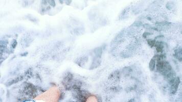 POV feet in water on the beach at the sea. Travel and vacation video