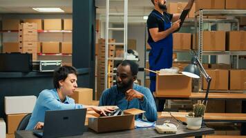 Diverse team of people preparing products order in storehouse space, woman signing inventory logistics files. Business owners using warehouse stock to ship to clients, financial planning. photo