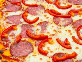 delicious pizza in the shape of pepperoni, salami, sausage, and pepper on a wooden table. top view photo