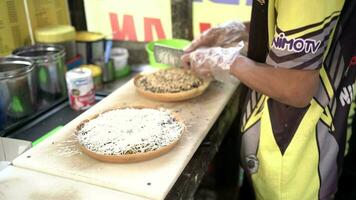 Surabaya, Indonesia, oct 09, 2023 - selectivo enfocar. proceso de haciendo dulce martabak con Leche queso sabor es por aspersión afeitado queso y endulzado condensado Leche en parte superior de el masa. video