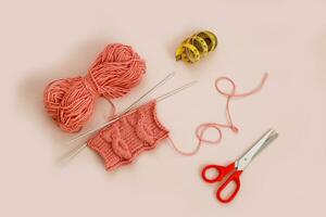 knitted pattern on knitting needles with scissors and measuring tape photo