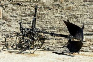 a plow is sitting against a stone wall photo