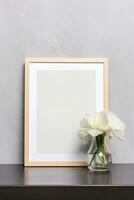 Blank vertical picture frame mockup hanging on a plain wall with wooden desk table and flower vase AI Generated photo