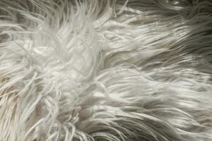 Close up artificial fluffy white-grey fabric fur, wool shaggy carpet with long pile. Soft loop pile surface. Hairy carpet detail. Faux fur texture, background. photo