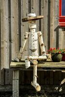 a wooden man sitting on a bench with a hat photo