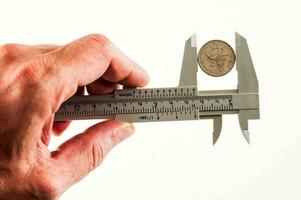 a person holding a caliper with a coin on it photo