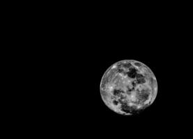 the moon is seen in black and white photo
