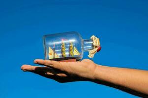 a man holding a small bottle with a miniature ship in it photo