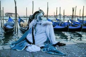 a woman dressed in white and blue sits on the ground next to gondolas photo