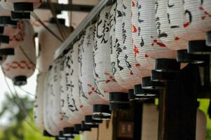 many paper lanterns hanging from a wooden pole photo