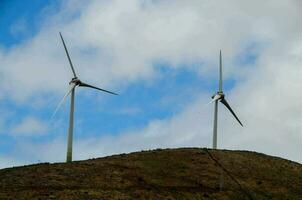 two wind turbines on top of a hill photo