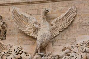 un estatua de un pájaro en el lado de un edificio foto