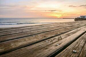un de madera paseo marítimo en el playa a puesta de sol foto