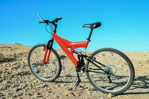 a red mountain bike is parked in the desert photo