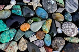 a variety of different colored stones are arranged on a black surface photo