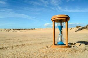 un reloj de arena en el arena en un soleado día foto