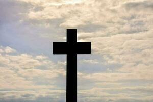 a cross is silhouetted against a cloudy sky photo