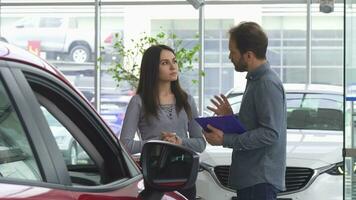 Mature salesman talking to his female customer offering her a car video