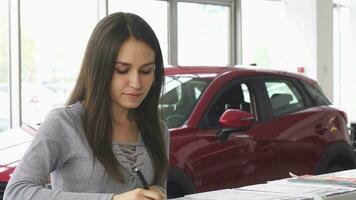 jovem atraente fêmea motorista o preenchimento papéis às a carro concessionária video