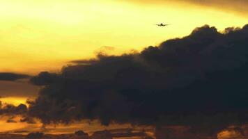 reclame vlak naderen landen. pittoreske zonsondergang, vlak in de lucht. vliegtuig silhouet tegen wolken. toerisme en reizen concept video