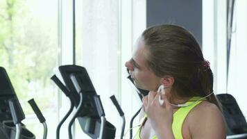 skön kvinna avtorkning henne nacke med en handduk efter träna på de Gym video