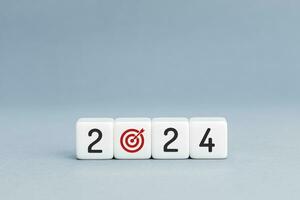 2024 business plan or goal concept. 2024 number and goal target icon on blocks isolated on blue background. Copy space photo