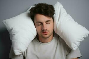 cansado hombre cubierta orejas con almohada en ligero gris despierto. generar ai foto