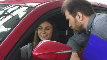 attraente donna seduta nel un' nuovo auto parlando per il venditore video