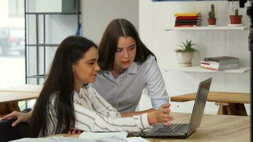 Beautiful businesswoman showing something on her laptop to a colleague video