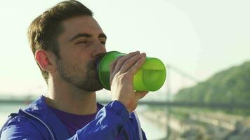 vicino su tiro di un' bello giovane uomo potabile acqua dopo Lavorando su video