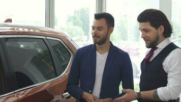 Two male friends discuaaing a new car at the dealership salon video