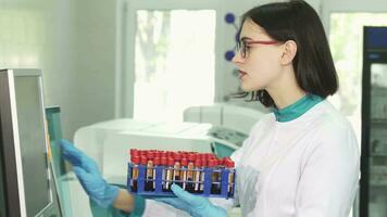 Young female scientist examining test tubes with blood samples video