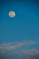 el Luna es visto en el azul cielo con nubes foto