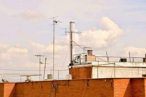 view of a brick fence in front of a building with antennas photo