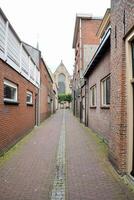 a narrow street with brick buildings and a church photo