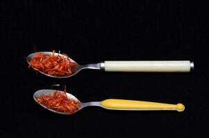 two spoons with dried saffron on a black background photo