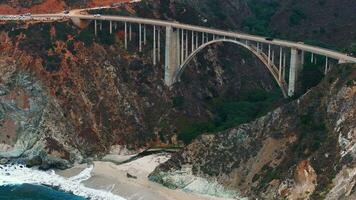 a pacífico oceano lavagens para a lindo Beira Mar do Califórnia, não longe sul do monterey. aéreo tiro do bixby Riacho ponte em a grande sur costa do Califórnia. video