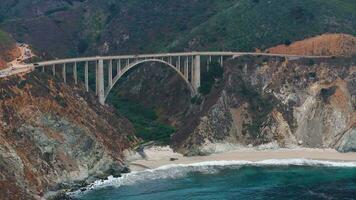 il Pacifico oceano lavaggi su il bellissimo riva del mare di California, non lontano Sud di monterey. aereo tiro di bixby torrente ponte su il grande sur costa di California. video